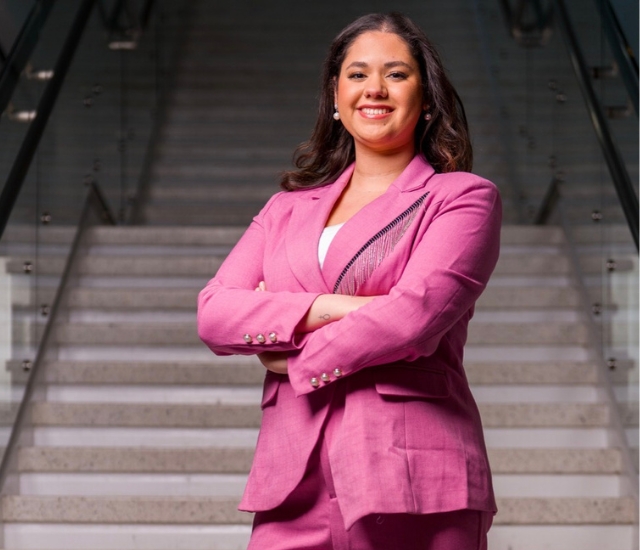 Student posing in pink business suit on stairs.