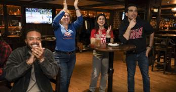 A group of alumni cheer together in a restaurant.