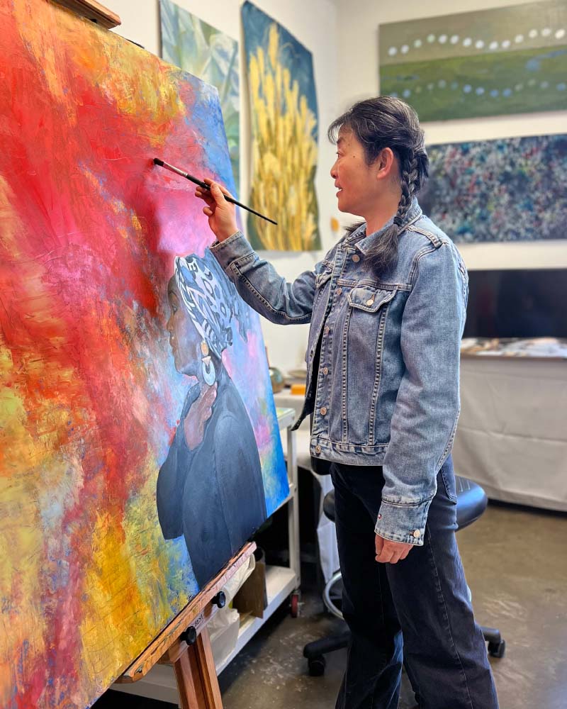 A woman works on a vibrant painting