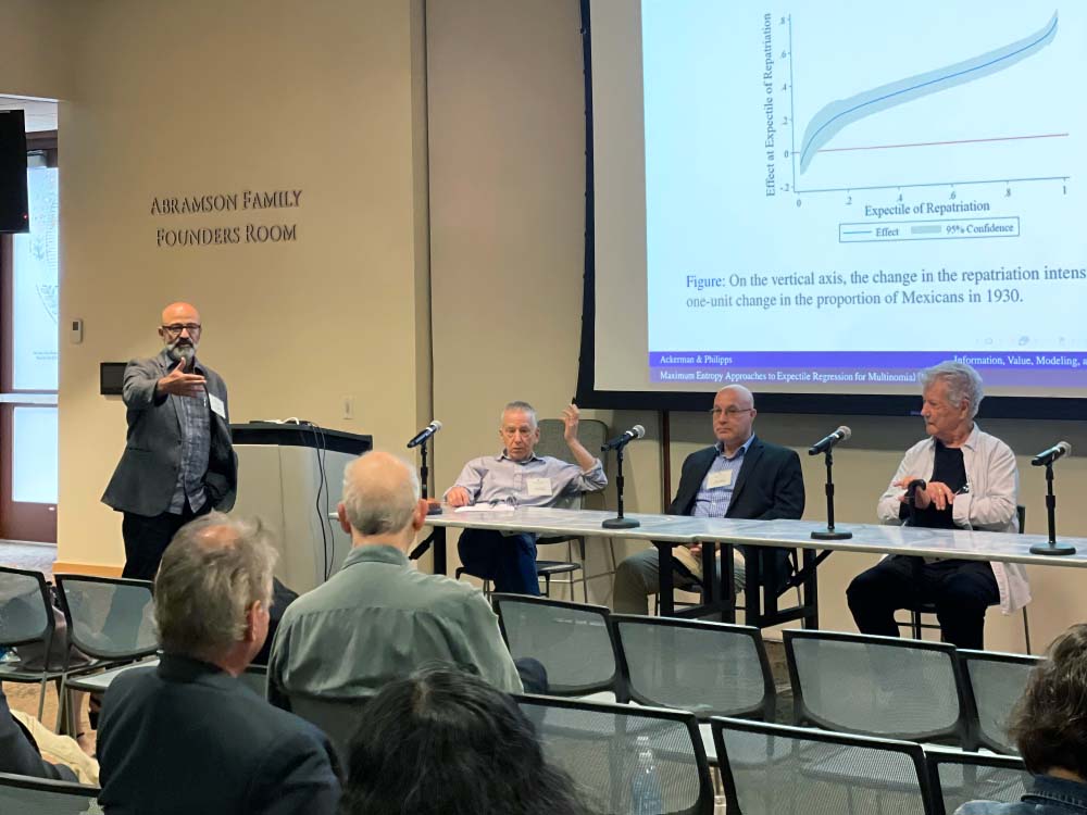 Round table speakers discussing in front of graph on projector screen