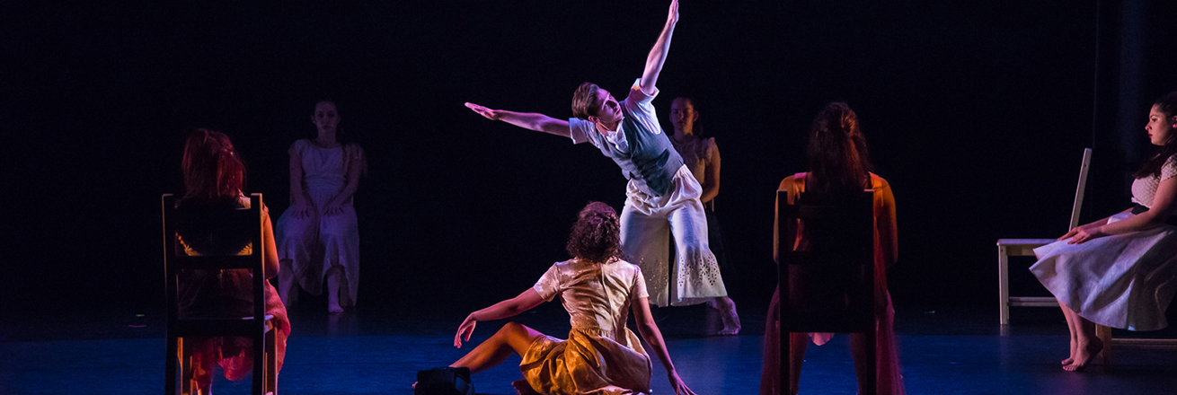 A man streches his arms wide as seated women look on