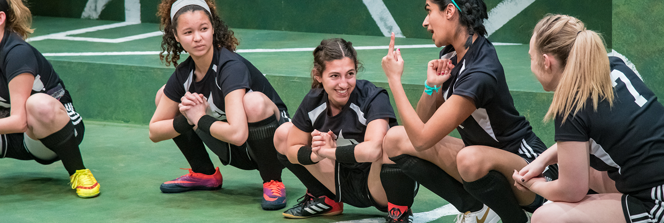 People in soccer uniforms stretch, giggling