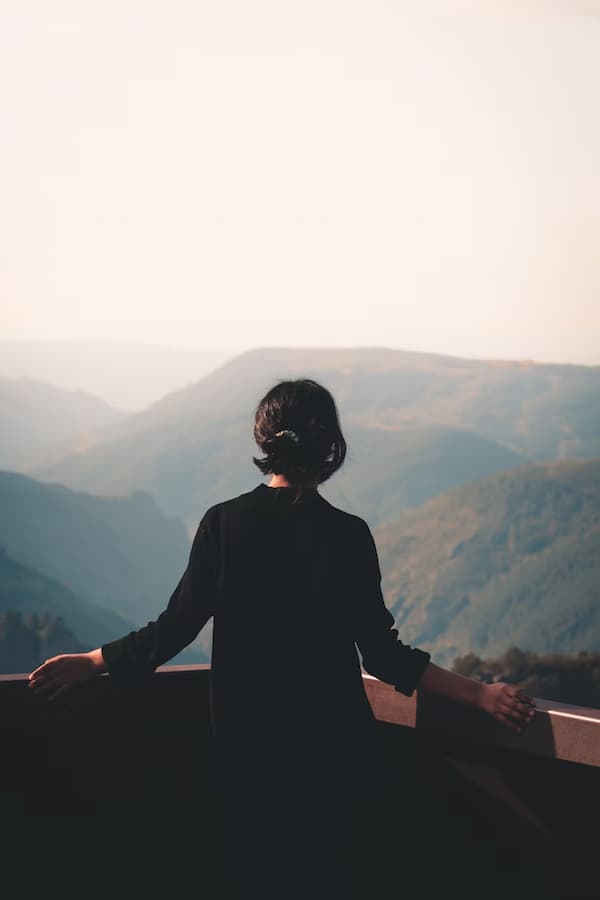 Woman viewing mountain overlook; credit: A.C. at Unsplash.