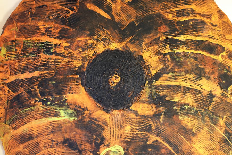 Patricia Edwine Poku, The Time Talisman, 2024. Scraped arcs of black on green and orange background. A spiral of rope at the center.