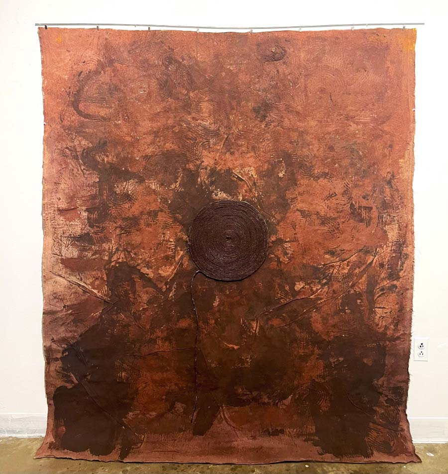 Patricia Edwine Poku, The Sand Talisman. A spiral of jute rope on a textured burnt red canvas. 