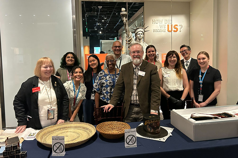 Catherine (far right) and Smithsonian colleagues in front of the 'How did we become US' exhibit, looking at historical objects including baskets out storage