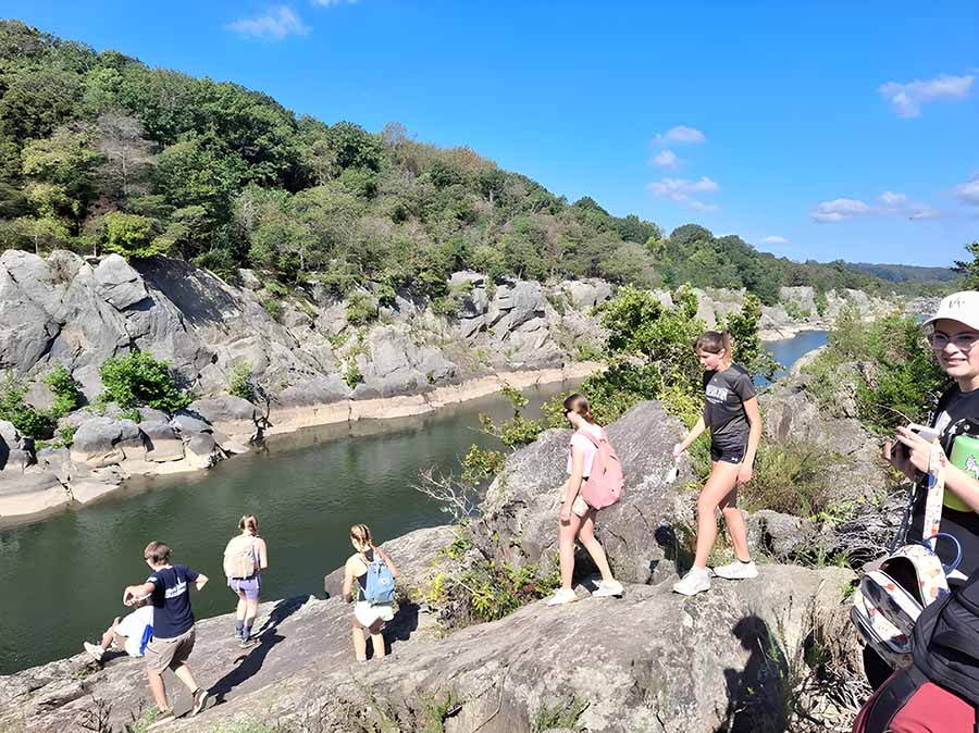 Students climb down rocks towards river