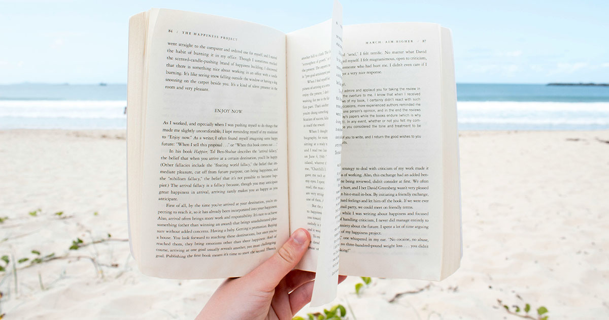 Hand holding an open book on the beach