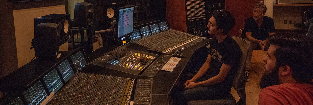 People at a soundboard watch a screen
