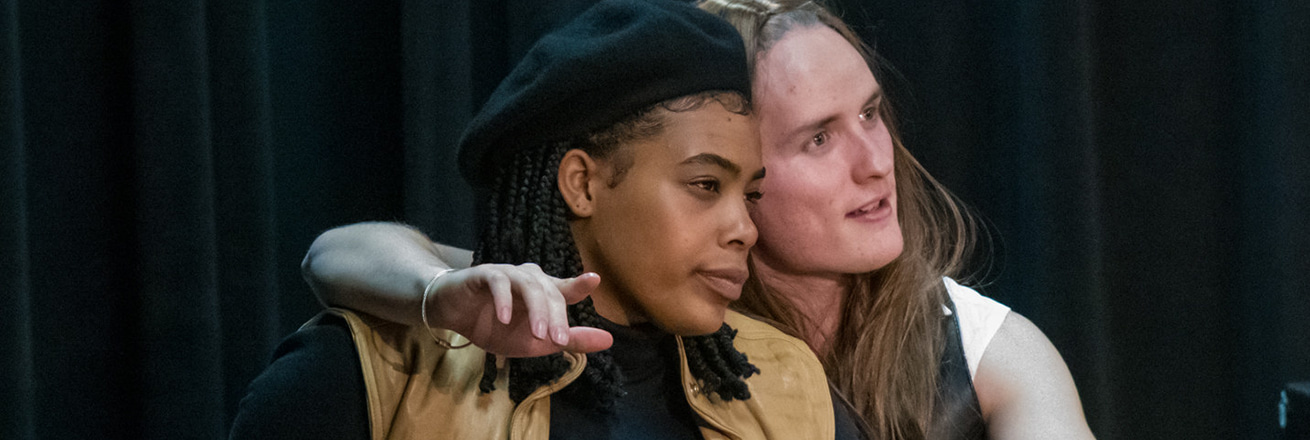 Two young people with long hair and a beret gaze into the future