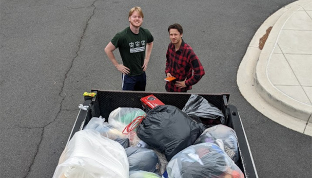 Project Move Out volunteers stand behind a container of donated items