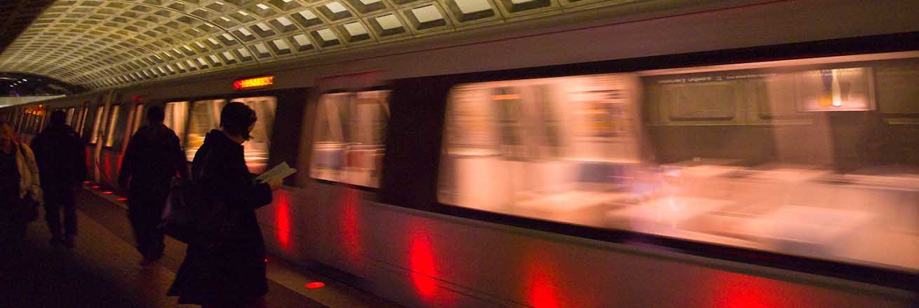 A metro train comes driving, with passengers waiting to board