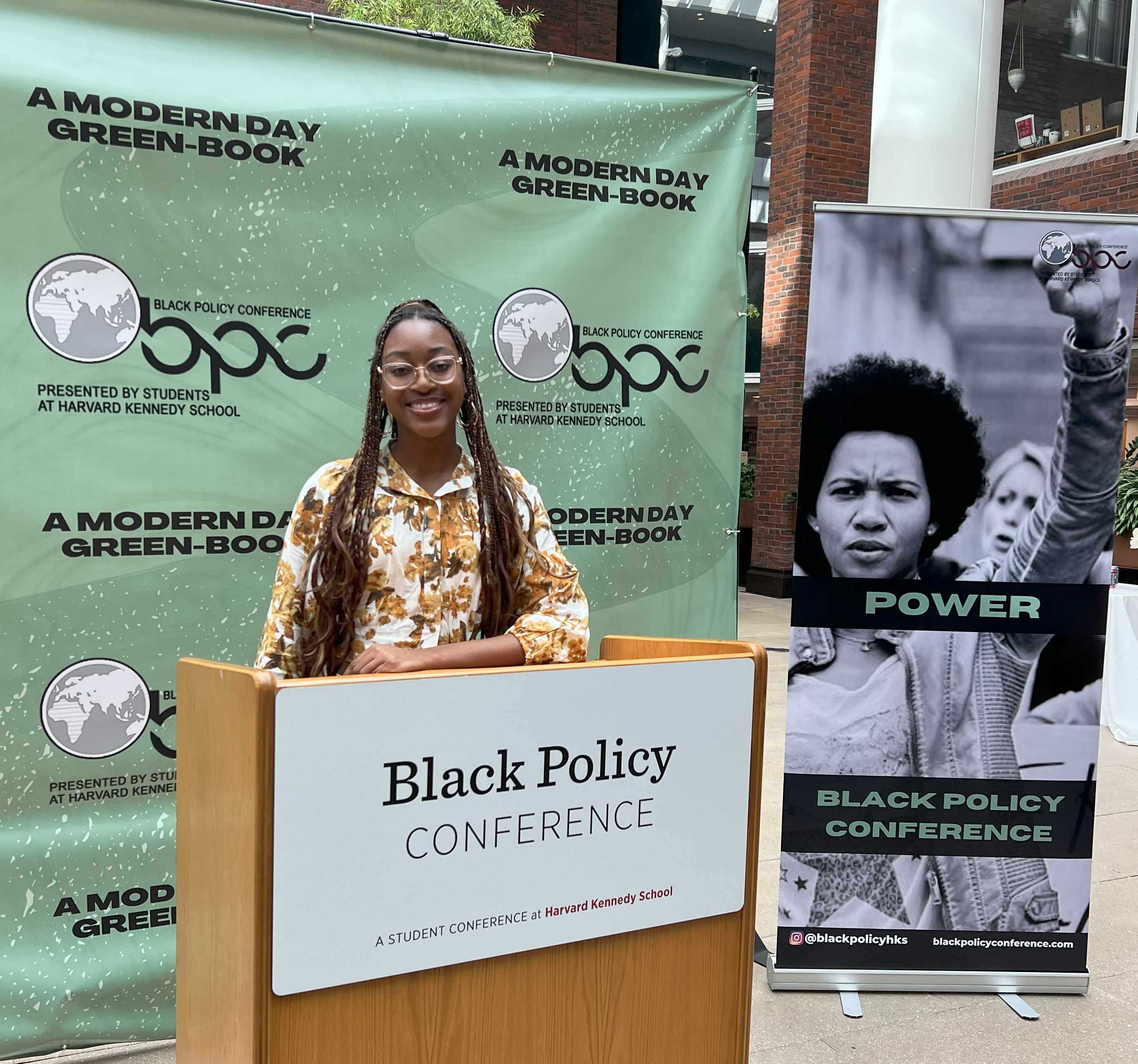 person standing behind podium, in front of sign