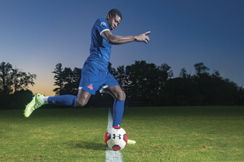 David Coly kicks a soccer ball at dusk at Reeves Field