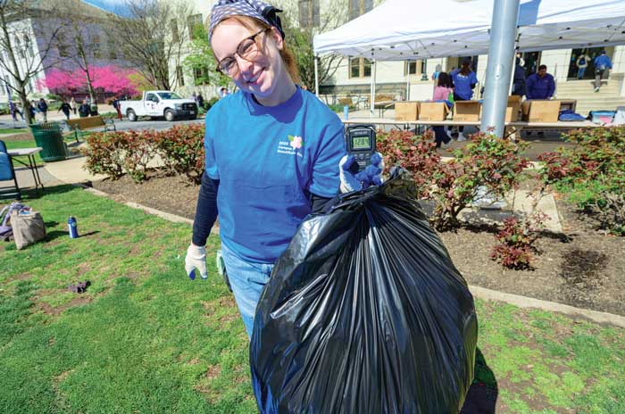 student holds up bag of trash on the quad