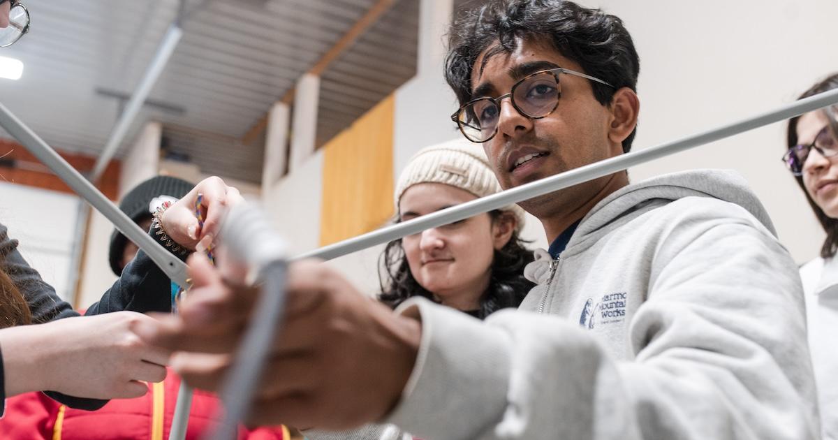 Ankur Purao, CAS/BS ’26, SIS/BA ’26, with students assembling the satellite dish. Photo by Nikolai Roster, CAS.