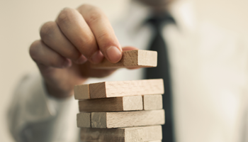 Male finger placing wooden puzzle pieces on top of one another