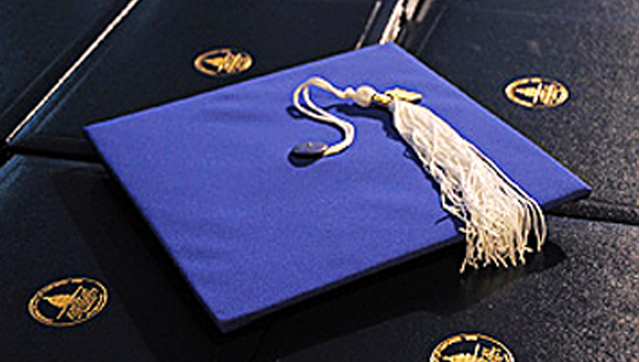 a blue graduation cap resting on top of diplomas.