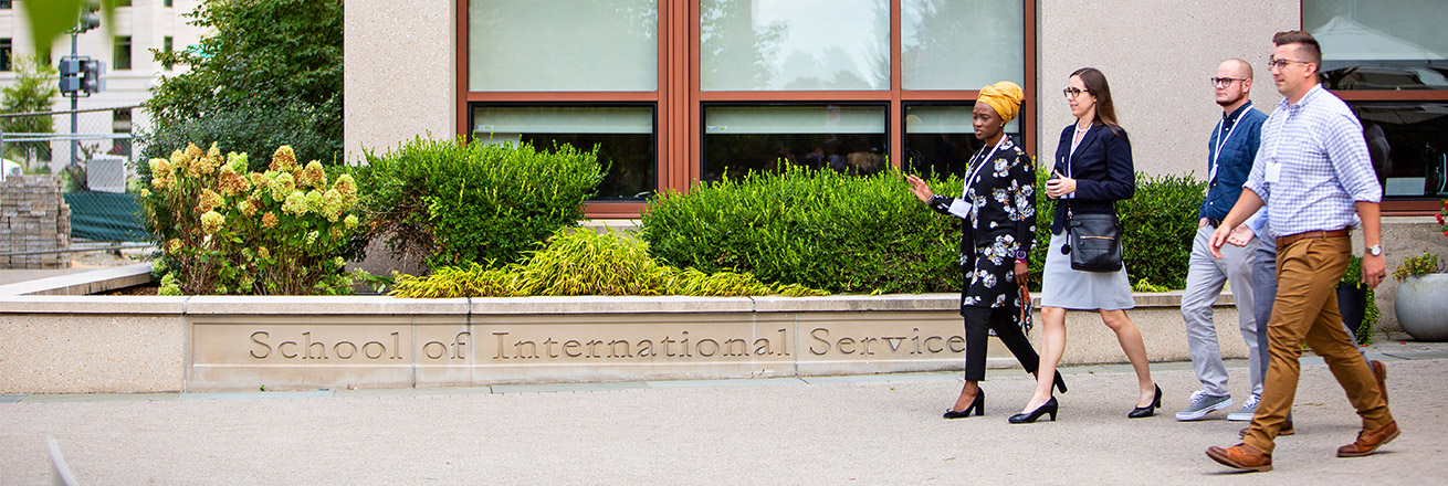 a group of four people walk outside the School of International Service building