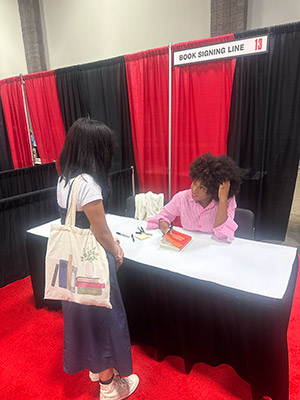 Author Chimamanda Ngozi Adichie signs a book for a student
