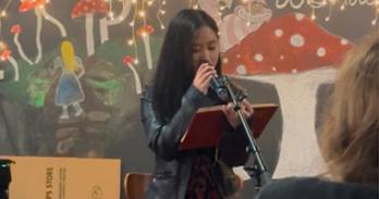 Ruchel Limbos reads to a crowd into a microphone from an open notebook