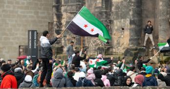 A man holds a large Syrian flag after the fall of the Assad regime.