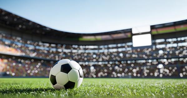 A soccer ball sits on an empty field in a stadium