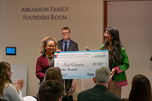 Two students in the Philanthropy Lab hold up an oversized check for Food for Education