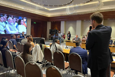 Henry Moskov speaks to the room with Prime Minister Modi listening on screen