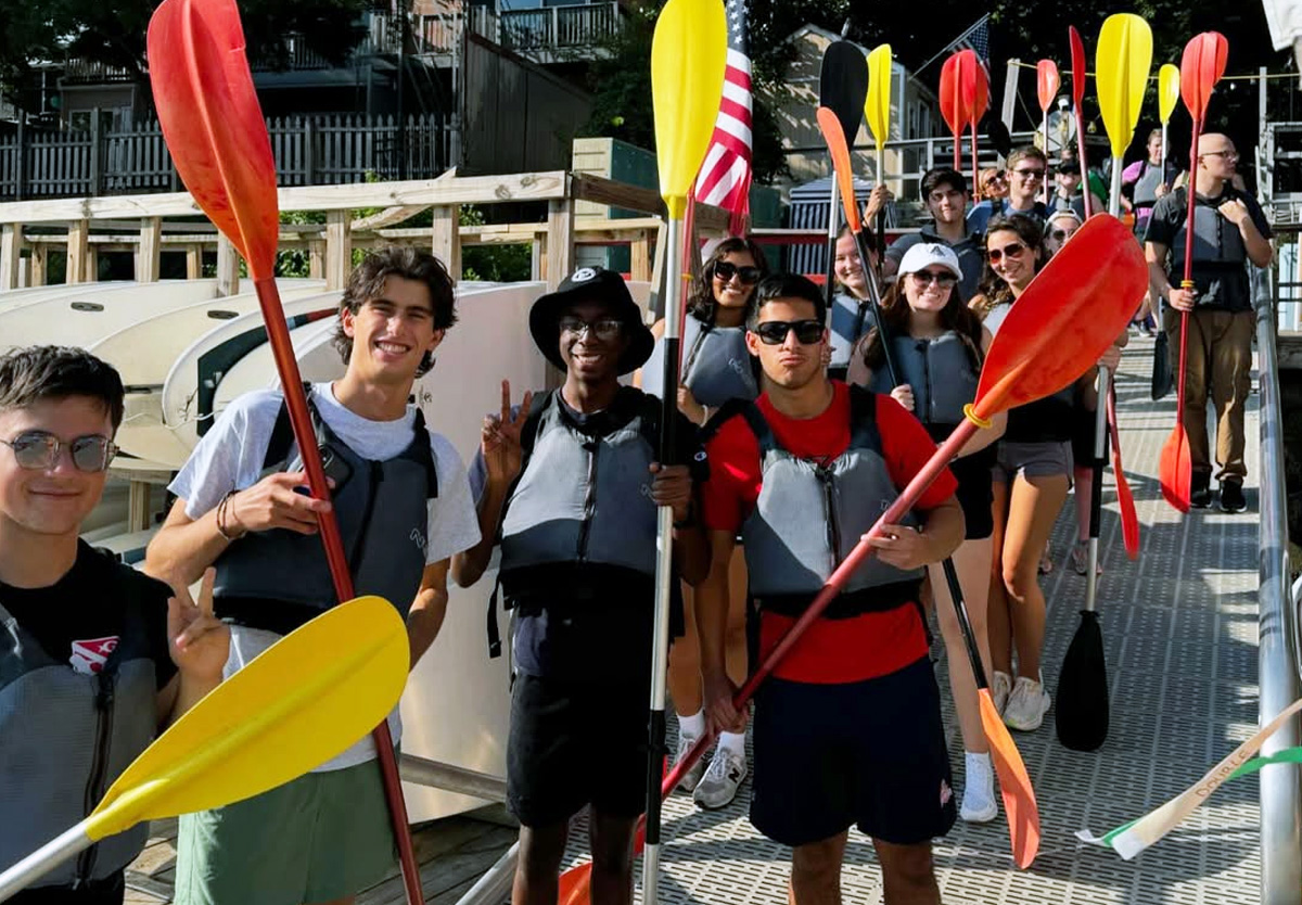 Global Scholars smile and hold oars before they kayak together.