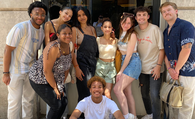A group of students smile outside of a restaurant in Madrid.
