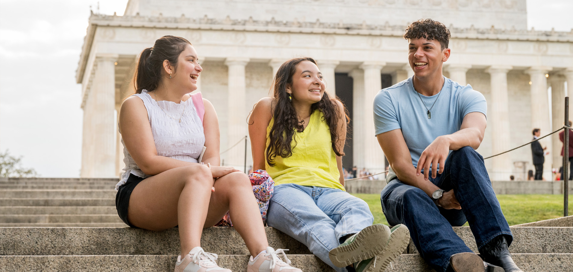 Three SIS students laugh and talk with each other in front of the Lincoln Memorial.
