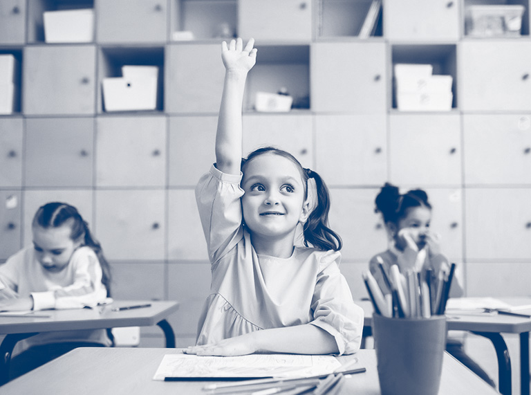 Young girl raises her hand in a classroom