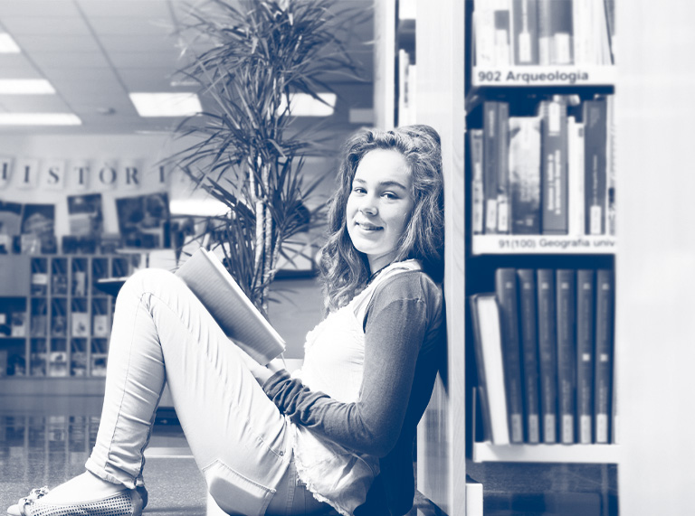 A girl reads a book in a library