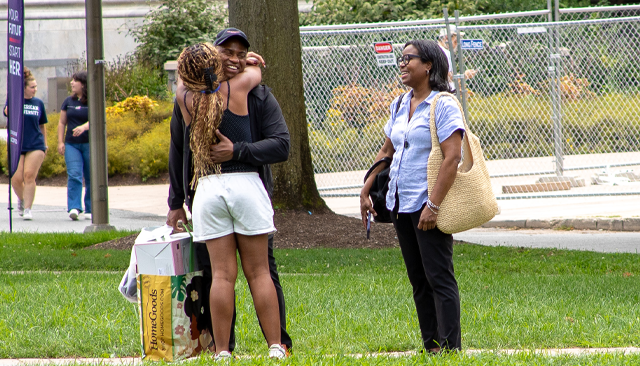 A student hugs one of her parents on the Quad.
