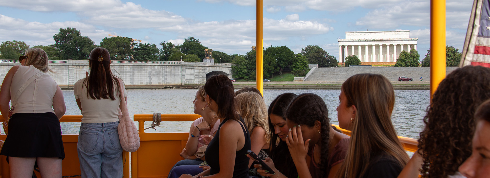 Students on a water taxi look across the Potomac at the Lincoln Memorial.